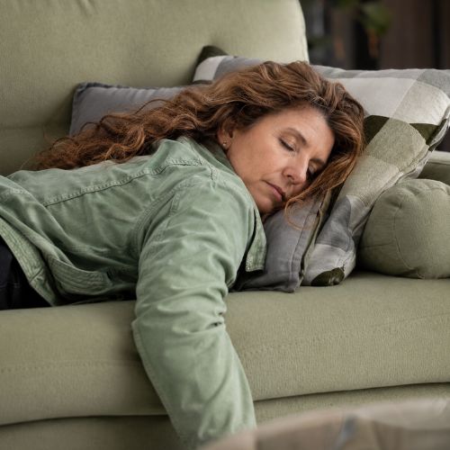 Erschöpfte Frau schläft auf dem Sofa – trotz gesundem Lebensstil